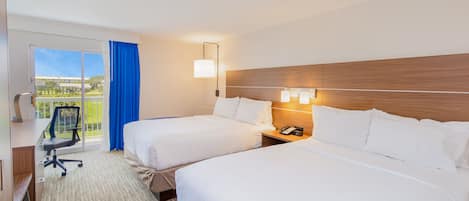 Een hotelkamer met twee bedden, een bureau, een stoel en uitzicht op de omgeving.