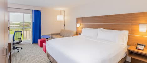 Une chambre d’hôtel avec un grand lit, un bureau avec une chaise, une petite table et un canapé.