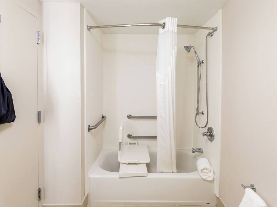 A standard hotel bathroom with a bathtub, shower, grab bars, and a towel rack.