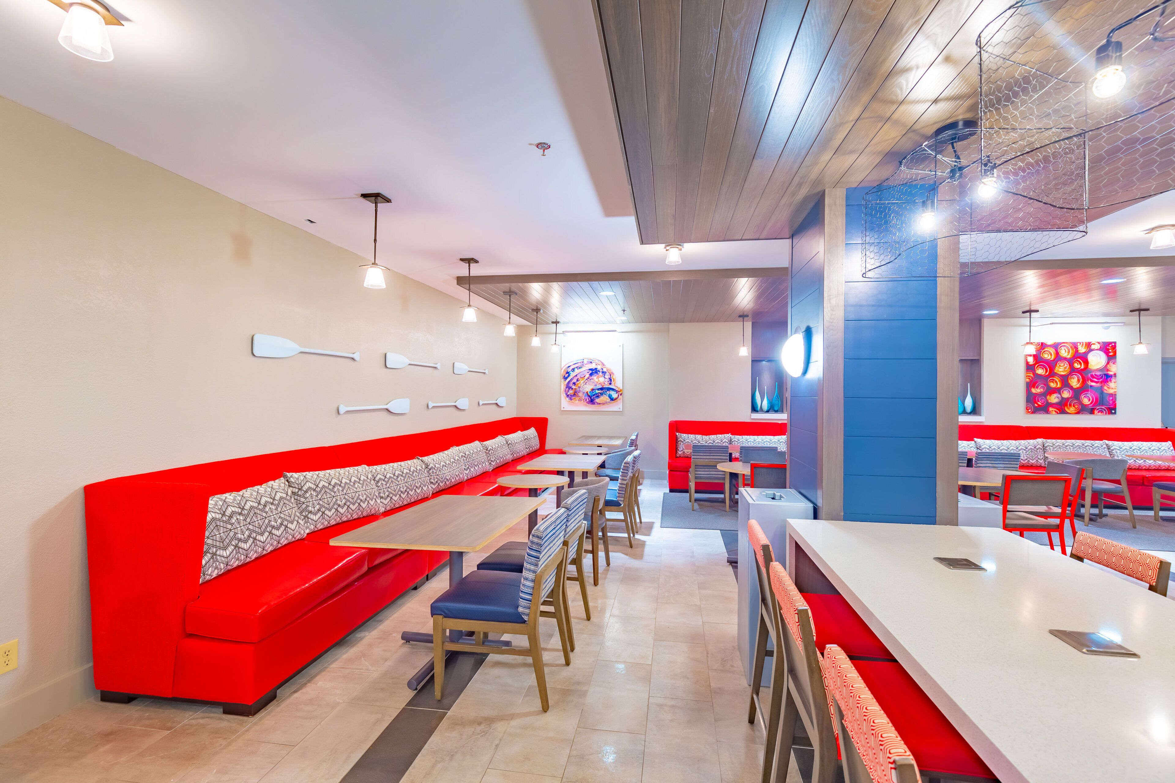 A restaurant with red booths, wooden tables, and a colorful mural on the wall.