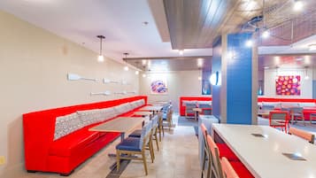 A restaurant with red booths, wooden tables, and a colorful mural on the wall.