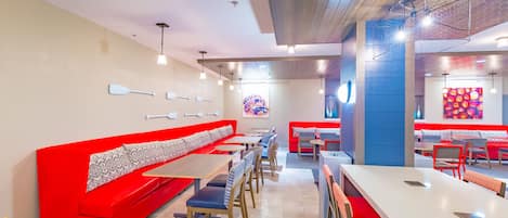 A restaurant with red booths, wooden tables, and a colorful mural on the wall.