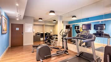 A fitness center with treadmills, a rowing machine, and a mirrored wall.