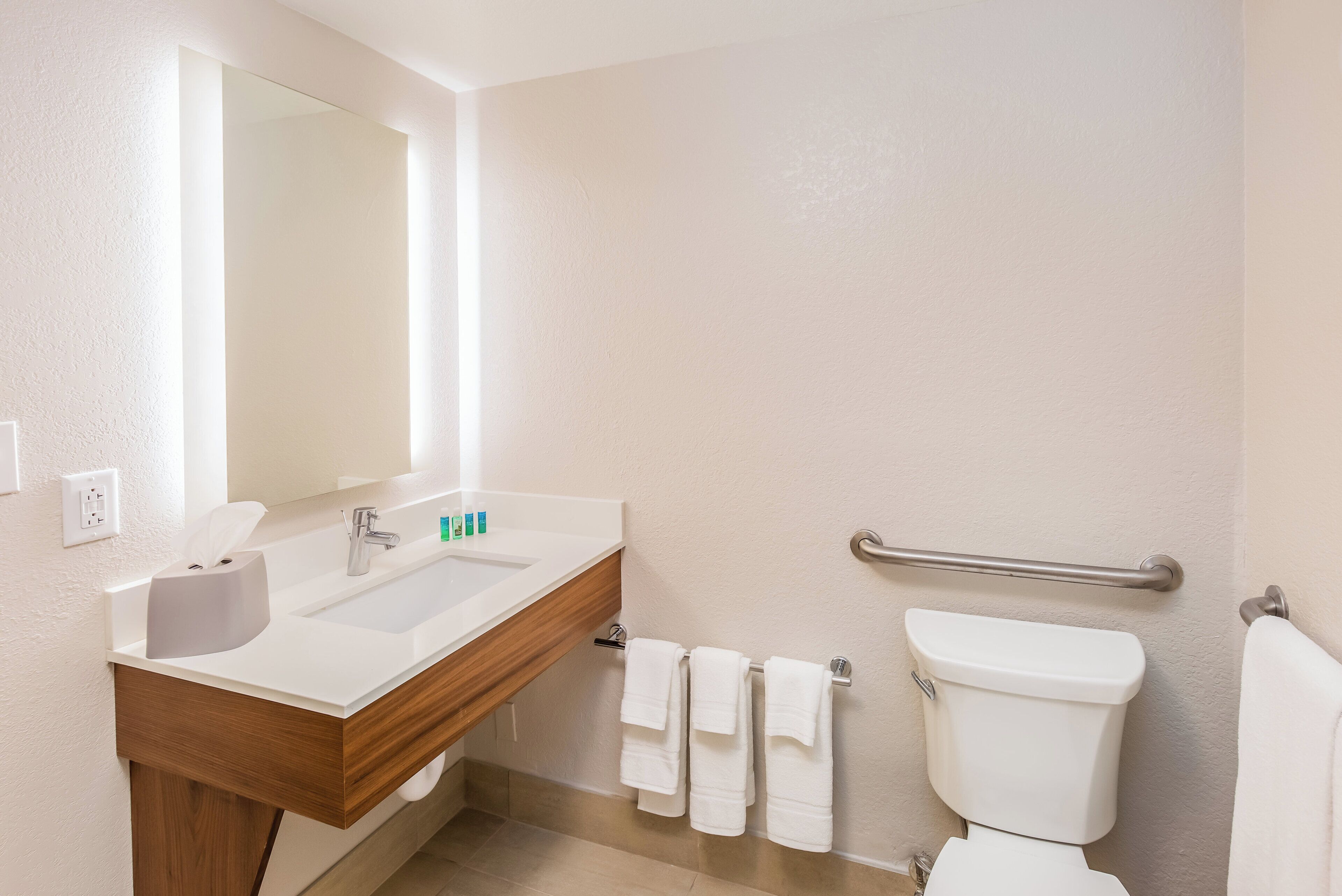 A bathroom with a sink, mirror, towel rack, and toilet.