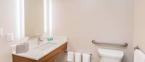Ein Badezimmer mit Waschbecken, Spiegel, Handtuchhalter und Toilette.
