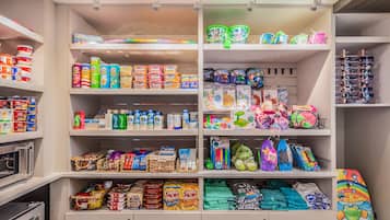 Un depósito trastero bien organizado con estantes que contienen diversos artículos como cajas de cereales, aperitivos y juguetes infantiles.