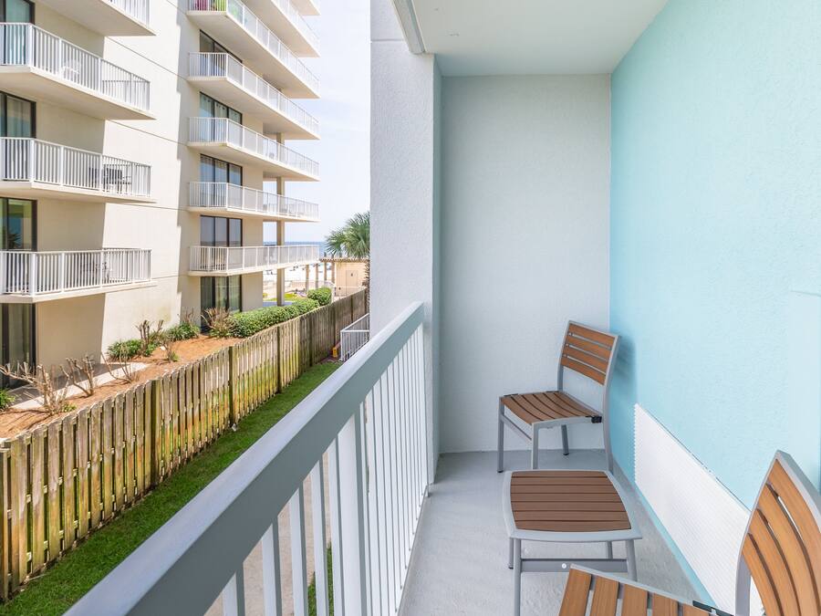 Un balcone con due sedie di legno e una ringhiera bianca.