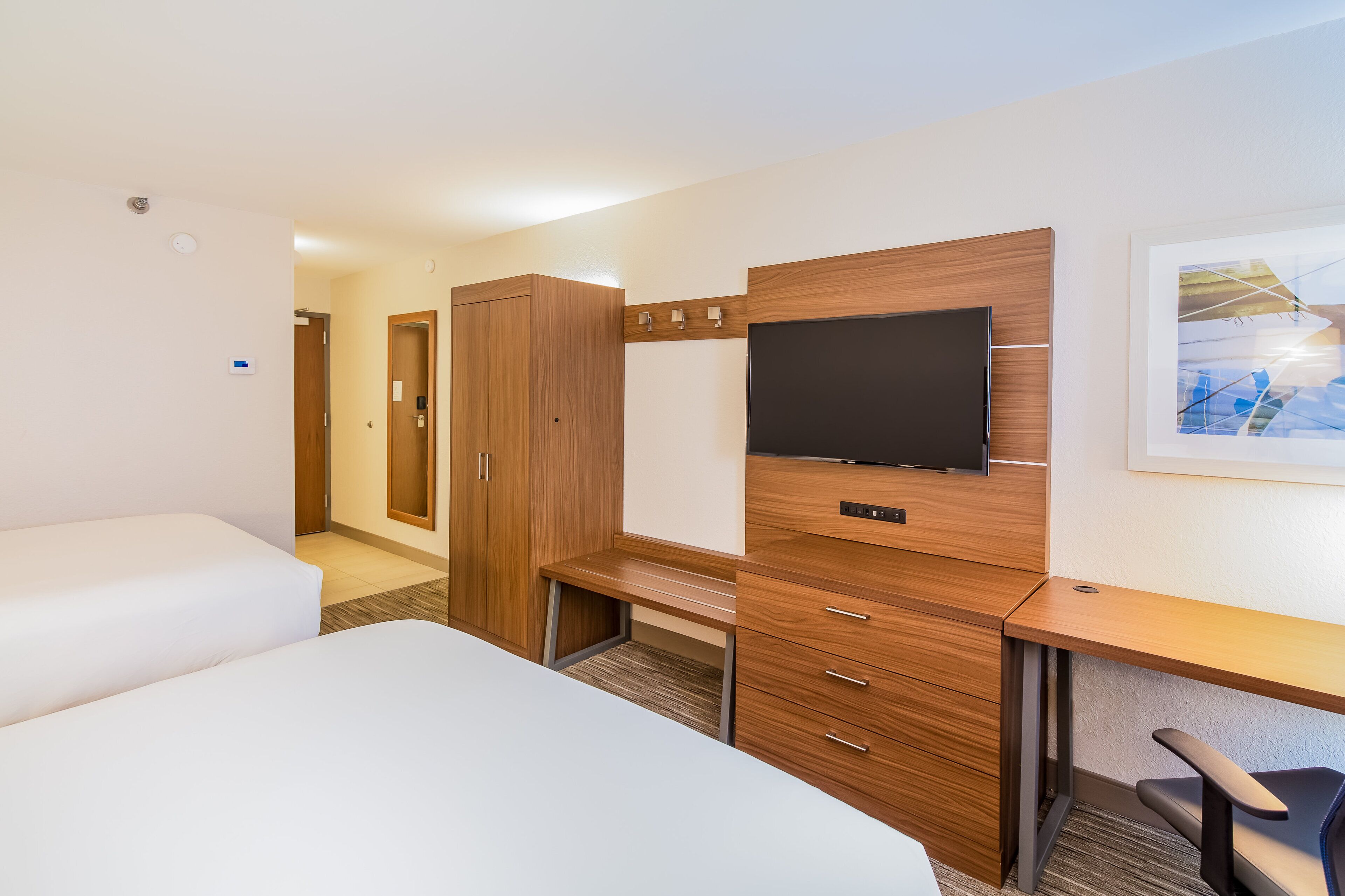 Una habitación de hotel con cama, escritorio, televisor y armario.