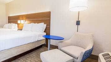 Una habitación de hotel con una cama, una mesita pequeña azul, una silla y un calentador.