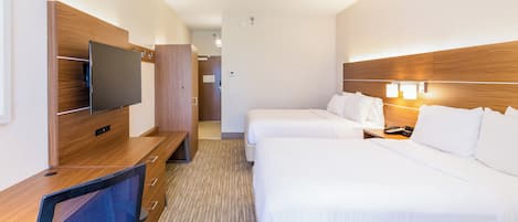 Quarto de hotel com escrivaninha, duas camas, televisão e banheiro.