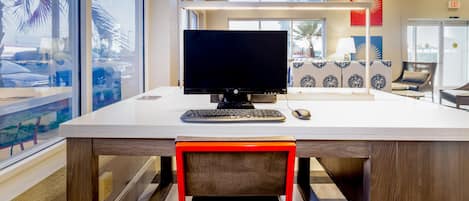 A modern office space with a large desk, computer, and chair.