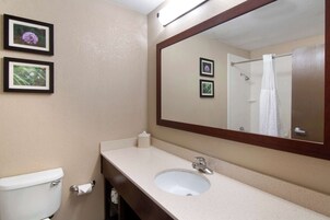 A bathroom with a toilet, sink, and mirror. There are two framed pictures on the wall.