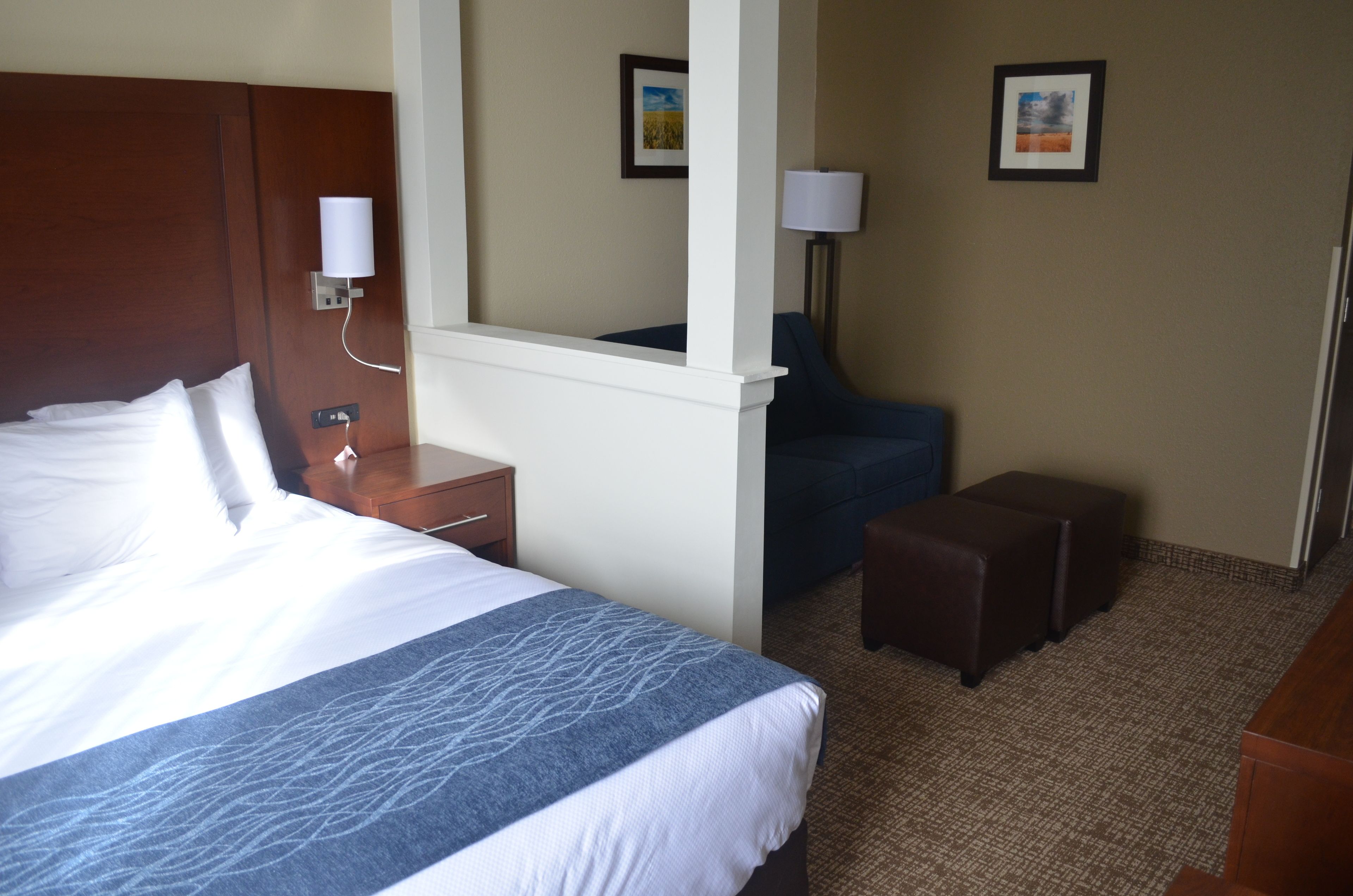 A hotel room with a large bed, a desk, a chair, and a small ottoman.