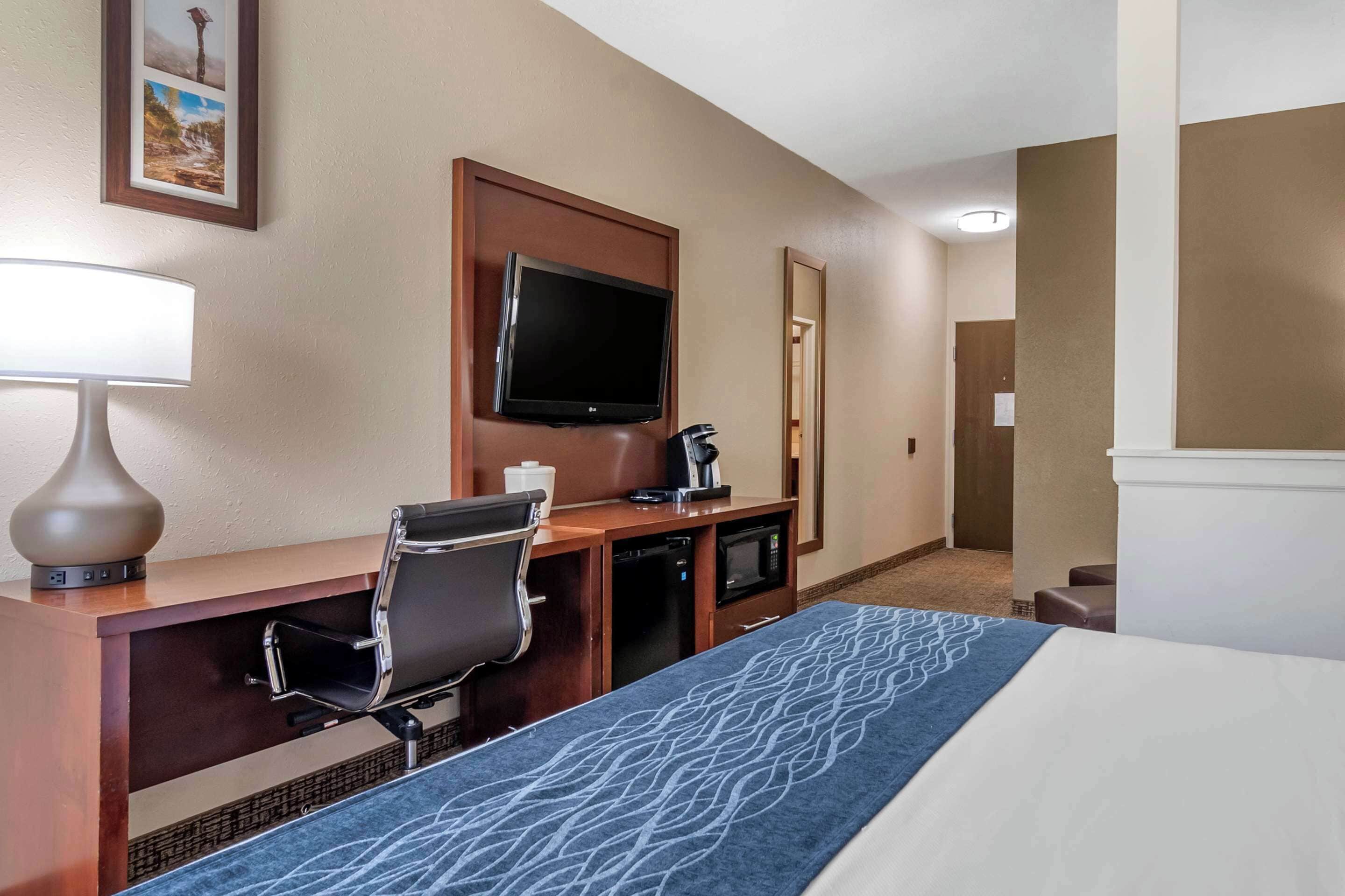 A hotel room with a bed, a desk with a chair, a television, a coffee maker, and a microwave.