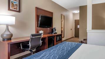 A hotel room with a bed, a desk with a chair, a television, a coffee maker, and a microwave.
