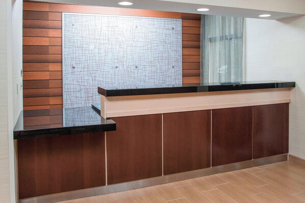 Un mostrador de recepción con un panel de madera de fondo y una partición de vidrio.
