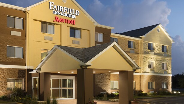 Een Fairfield Inn & Suites Marriott hotel met een overdekte ingang, meerdere ramen en een parkeerplaats.