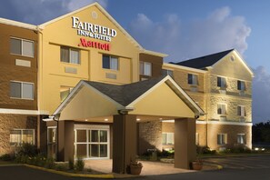 Un hotel Fairfield Inn & Suites Marriott con entrada techada, varias ventanas y un estacionamiento.
