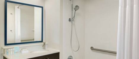 Un baño moderno con un lavabo blanco, un espejo grande con marco azul, un cabezal de ducha de mano y una barra de apoyo.
