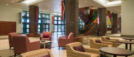 A spacious lobby with comfortable seating, a staircase, and large windows.
