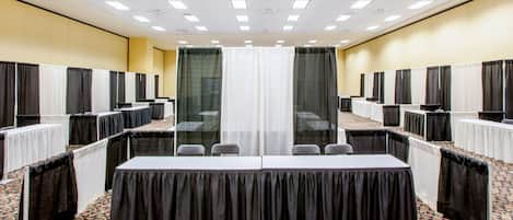 A conference room with a long table, chairs, and partition curtains.