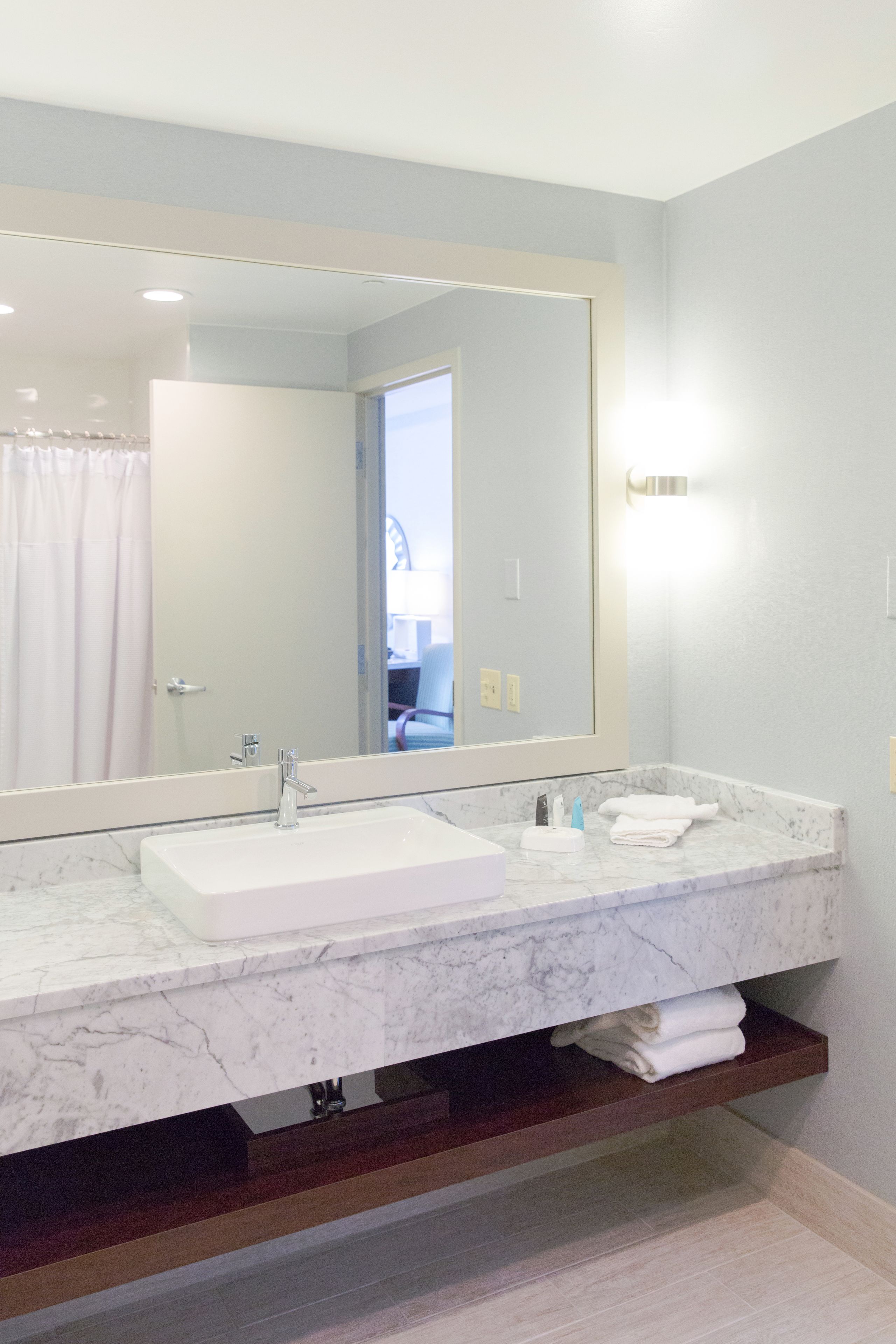 A bathroom with a large mirror, two sinks, and a towel rack.