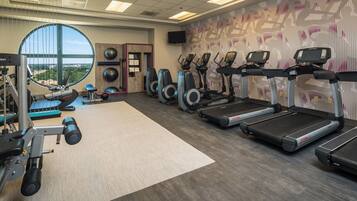 A gym with treadmills, elliptical machines, and free weights.