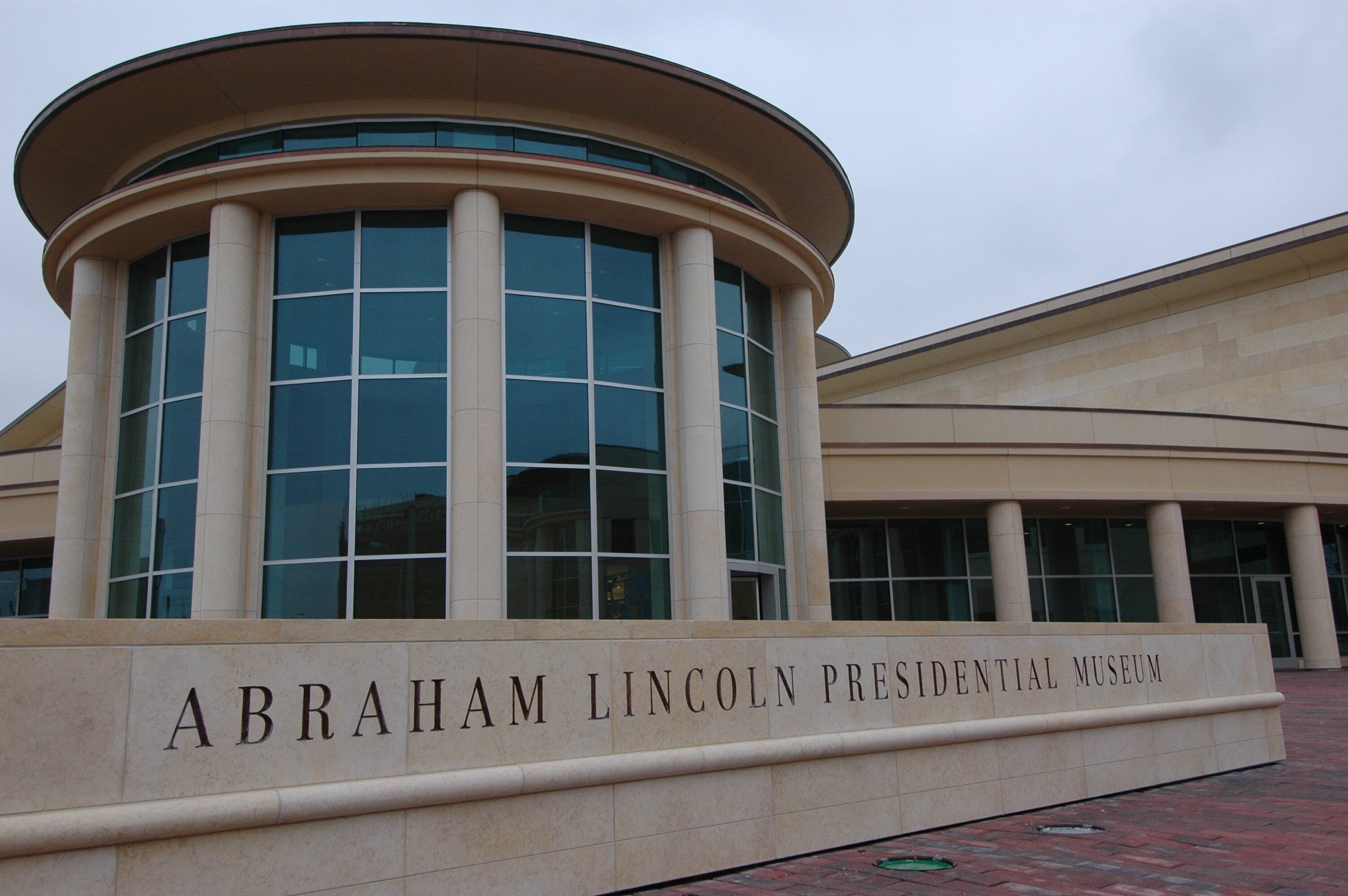 Un edificio con fachada curva, ventanas amplias y un cartel que dice 'Abraham Lincoln Presidential Museum'.