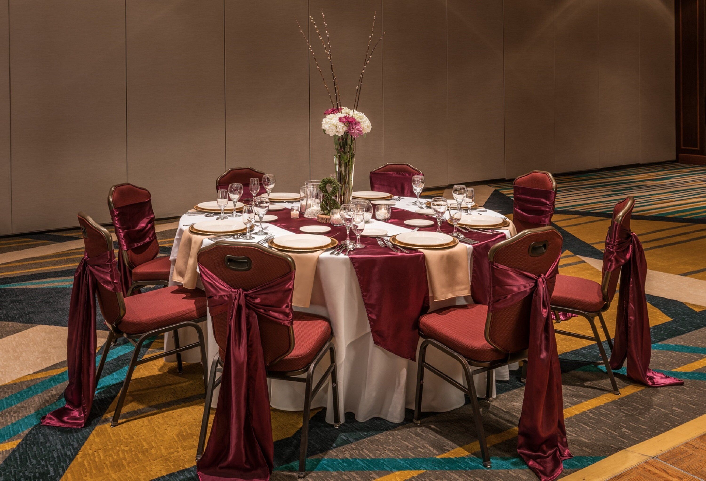 A round table set for a formal dinner with red chairs and a white tablecloth.