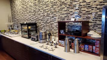 A breakfast buffet area with a variety of food options, including cereal, milk, and bread.