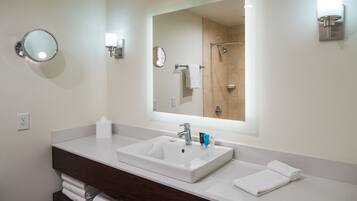 A bathroom with a large mirror, a sink, and a towel rack.