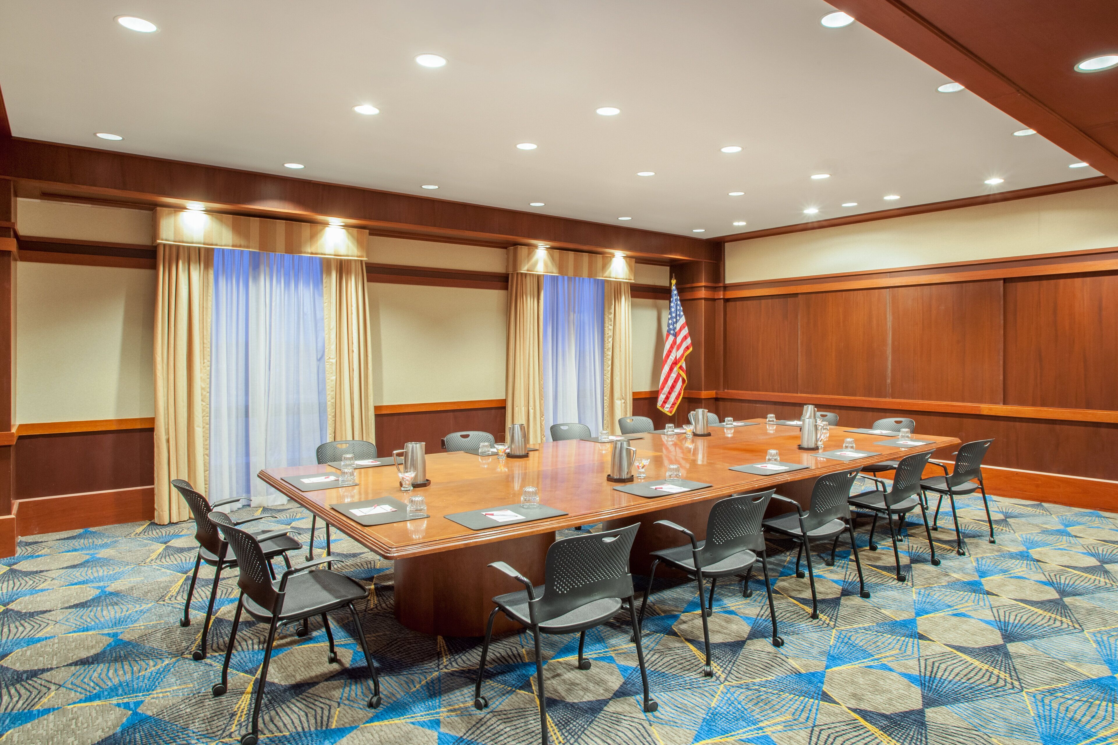 Une salle de conférence avec une longue table, des chaises et un drapeau américain.