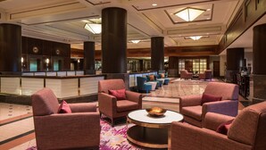 A spacious lobby with multiple seating areas, a reception desk, and a large chandelier.