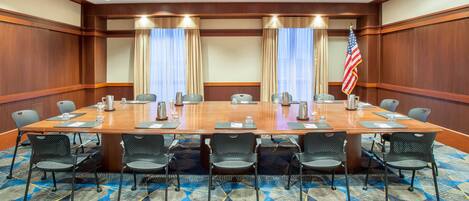 A conference room with a long table, chairs, and an American flag.