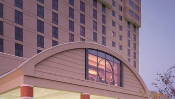 A modern hotel with a large entrance, multiple floors, and a distinctive arched overhang above the lobby.
