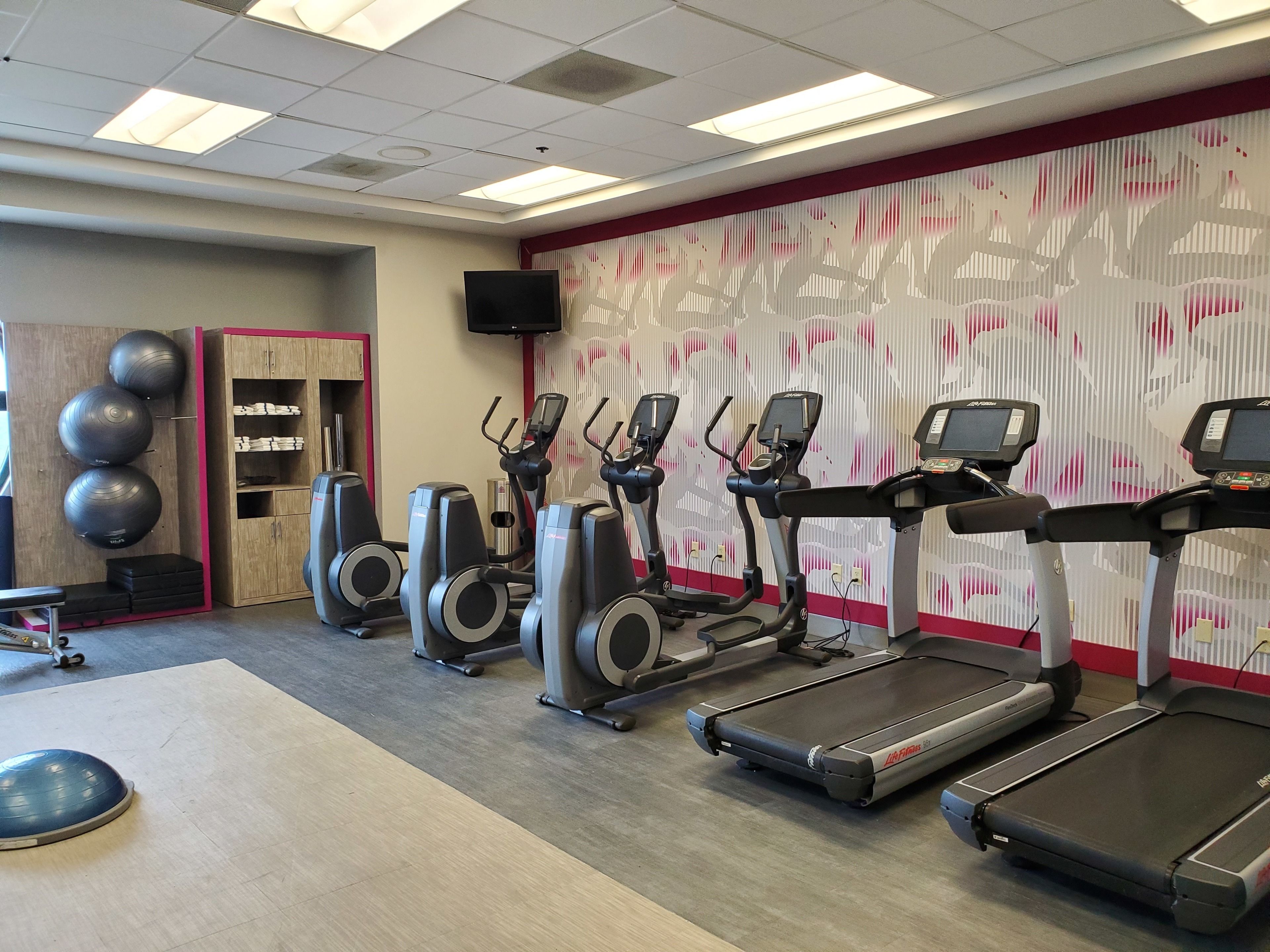 Ein Fitnessraum mit Laufbändern, Crosstrainern und Fitnessbällen.