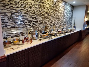 A buffet setup with various food items and condiments.