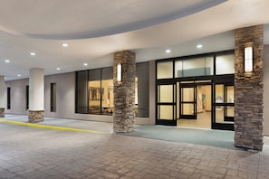 A building entrance with stone pillars, large windows, and a flat roof.