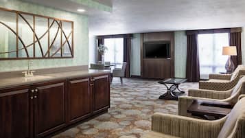 A hotel room with a wooden cabinet, a flat-screen TV, a sofa, and a patterned carpet.