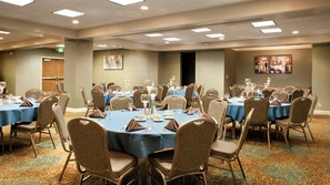 A conference room with round tables, chairs, and table settings. - Holiday Inn Rock Island by IHG (Rock Island)