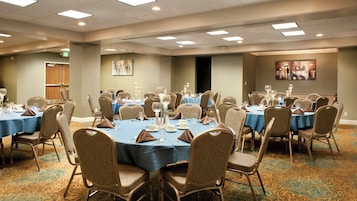 Un salón de conferencias con mesas redondas, sillas y un montaje para la comida.