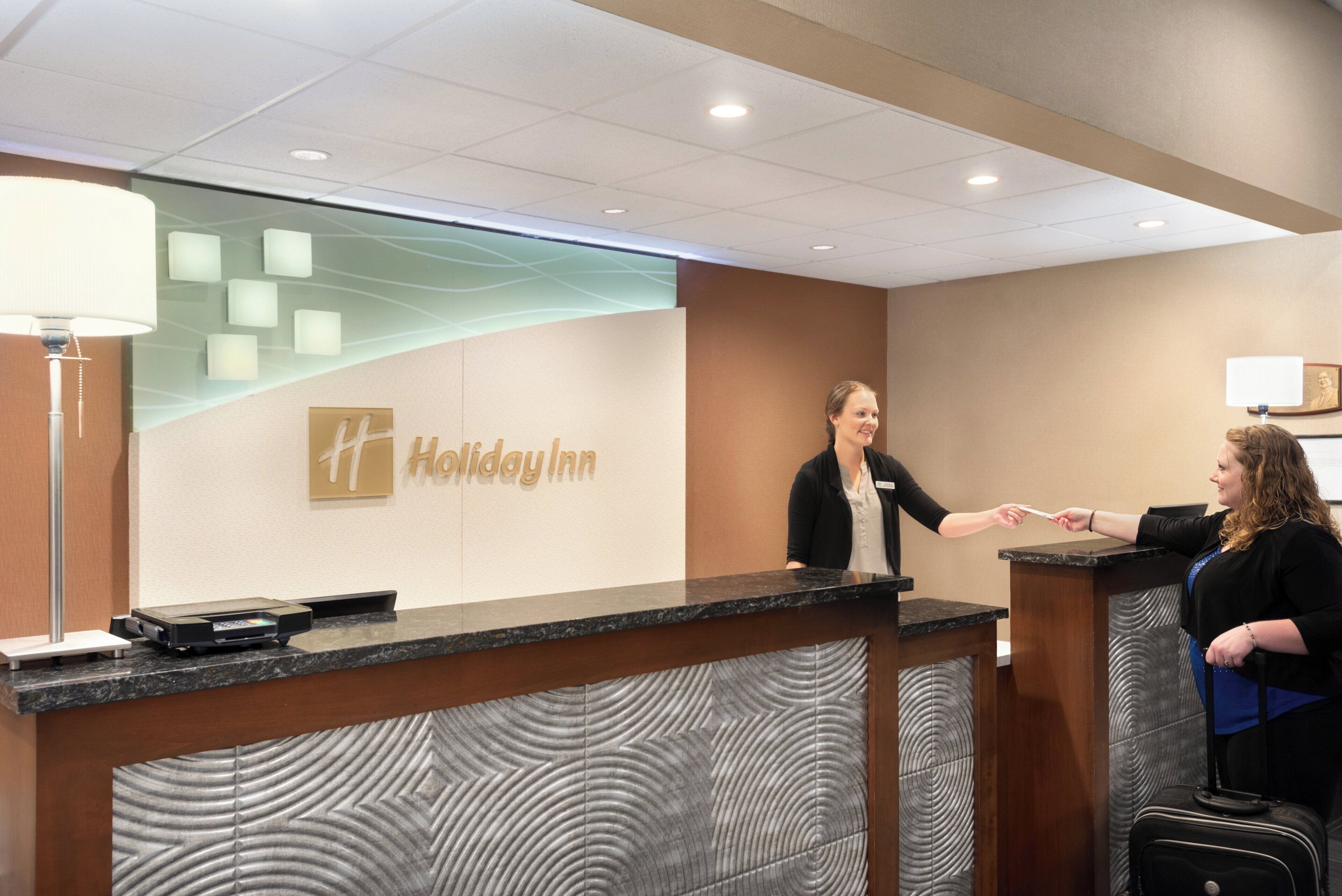 Un mostrador de recepción de Holiday Inn con una placa, una pantalla digital y una barra.