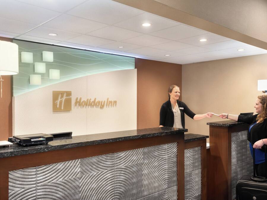 Een receptiebalie van Holiday Inn, met een naambordje, een scherm en een toonbank.