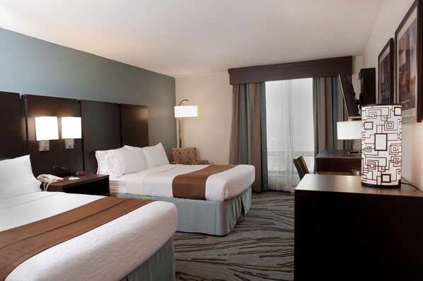 A hotel room with two beds, a desk, a lamp, and a view of the outdoors. - Holiday Inn Rock Island by IHG (Rock Island)
