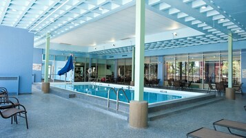 An indoor swimming pool with a covered area, exercise equipment, and seating.