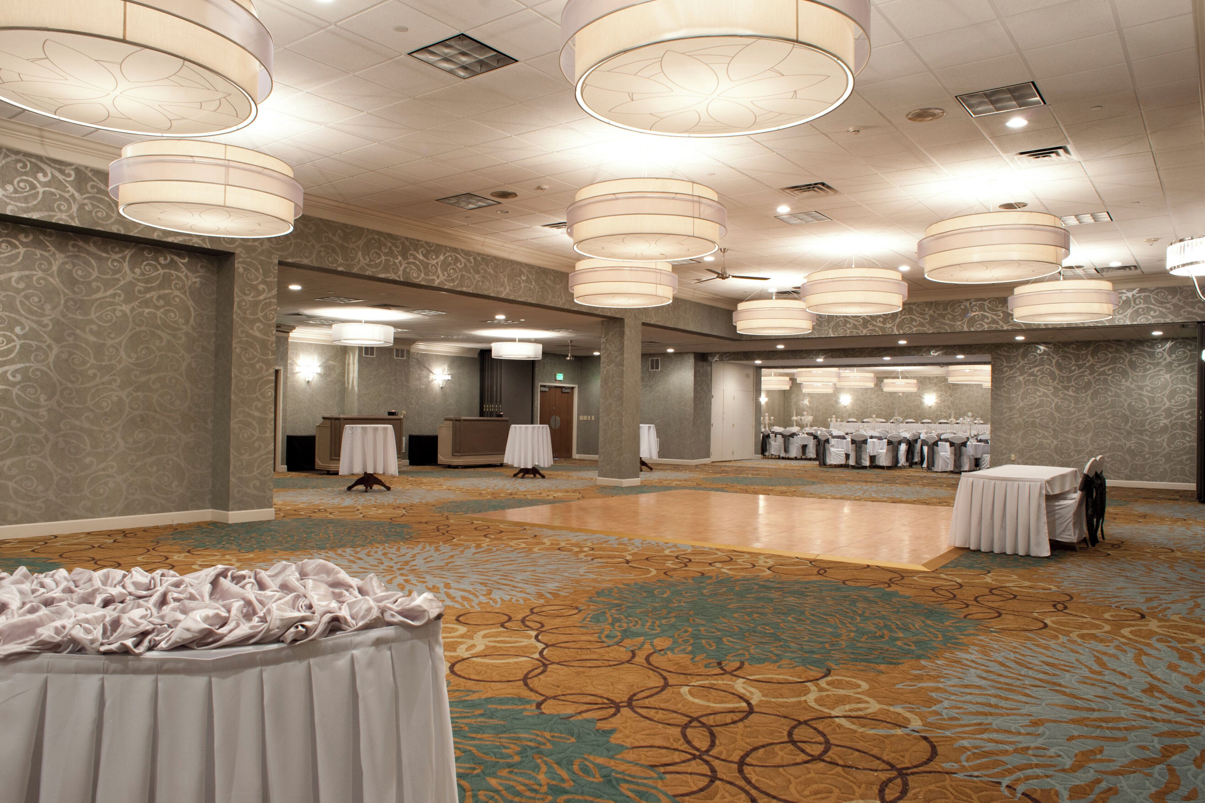 A spacious hall with multiple tables and chairs, a reception desk, and a patterned carpet.