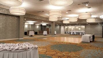 A spacious hall with multiple tables and chairs, a reception desk, and a patterned carpet.