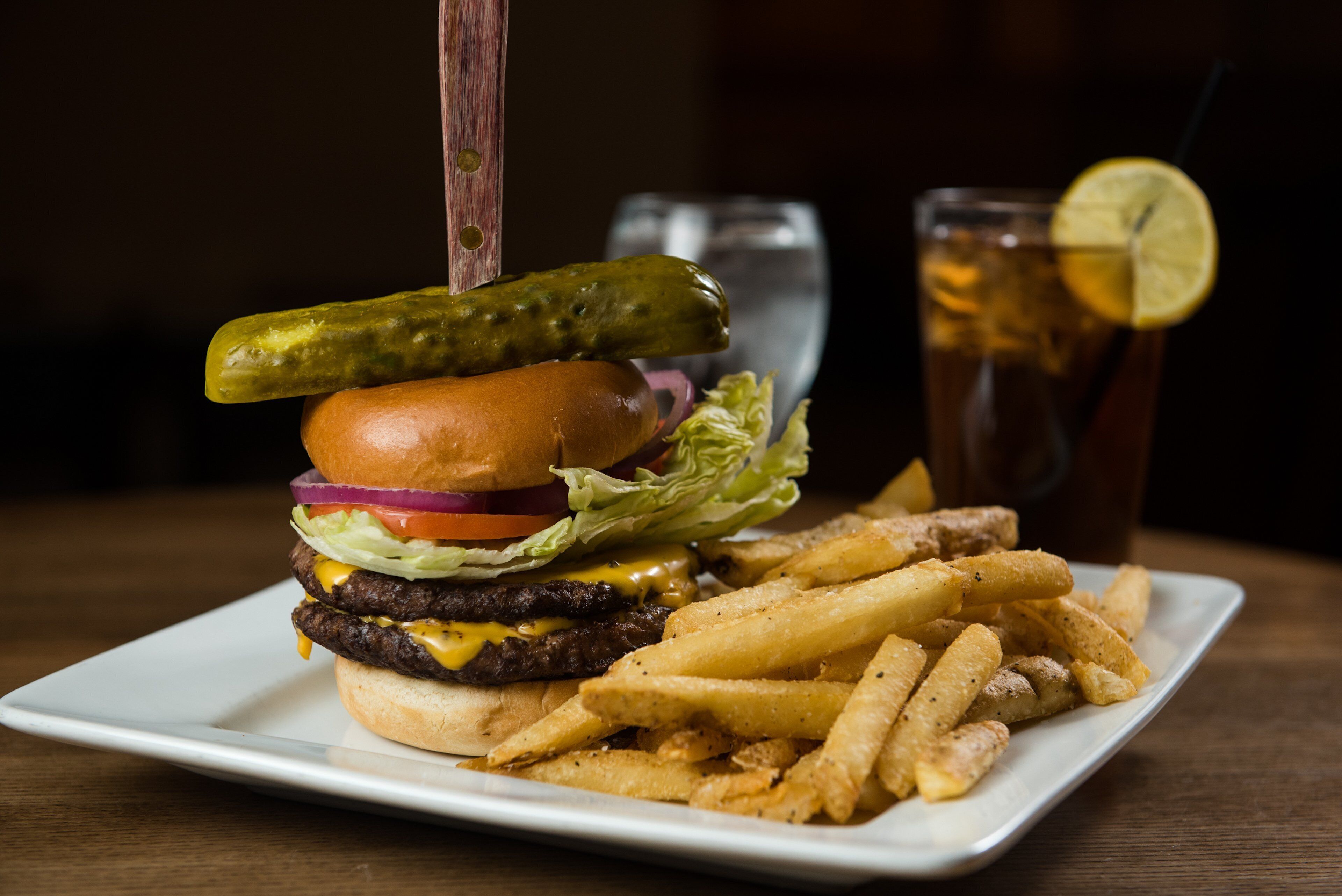 Une assiette avec un hamburger, des frites et une boisson.