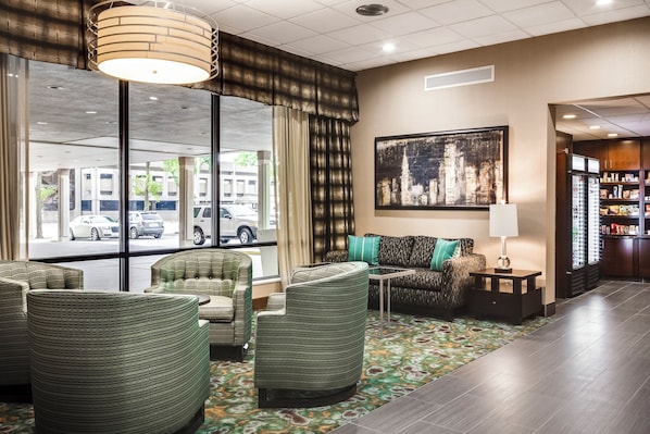 A hotel lobby with seating, a large window, and a painting on the wall.
