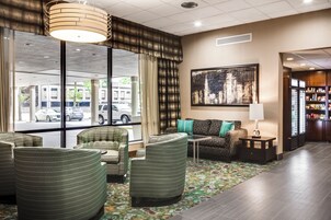 A hotel lobby with seating, a large window, and a painting on the wall.